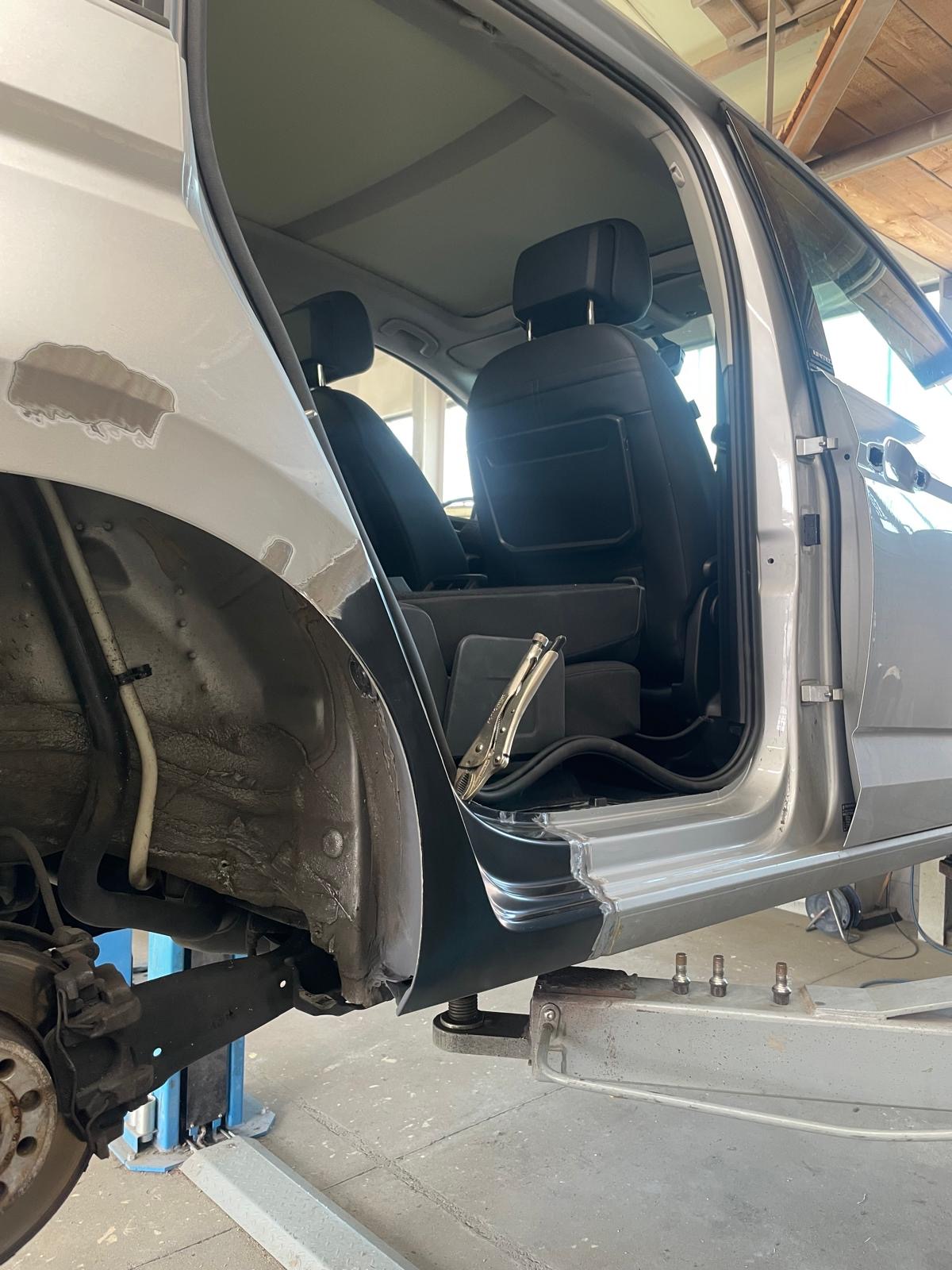 Silberner Kompaktwagen auf der Hebebühne mit offener Tür — Schweller-Reparatur freigelegt