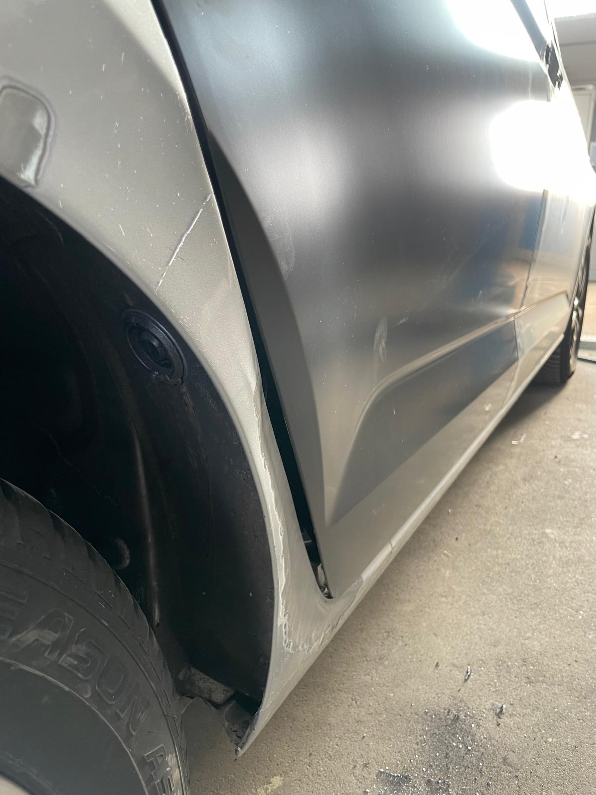 Silberne Limousine mit beschädigtem Kniestück und schwarz grundierter Tür hinten rechts vor der Reparatur