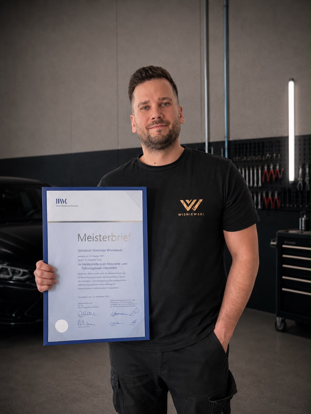 Karosseriebaumeister Sebastian Wisniewski mit Meisterbrief in seiner Werkstatt in Sprockhövel